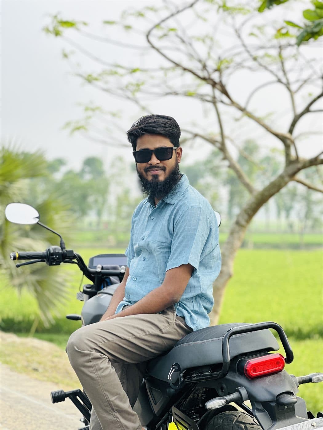 RH Razu sitting on his motorbike by green fields